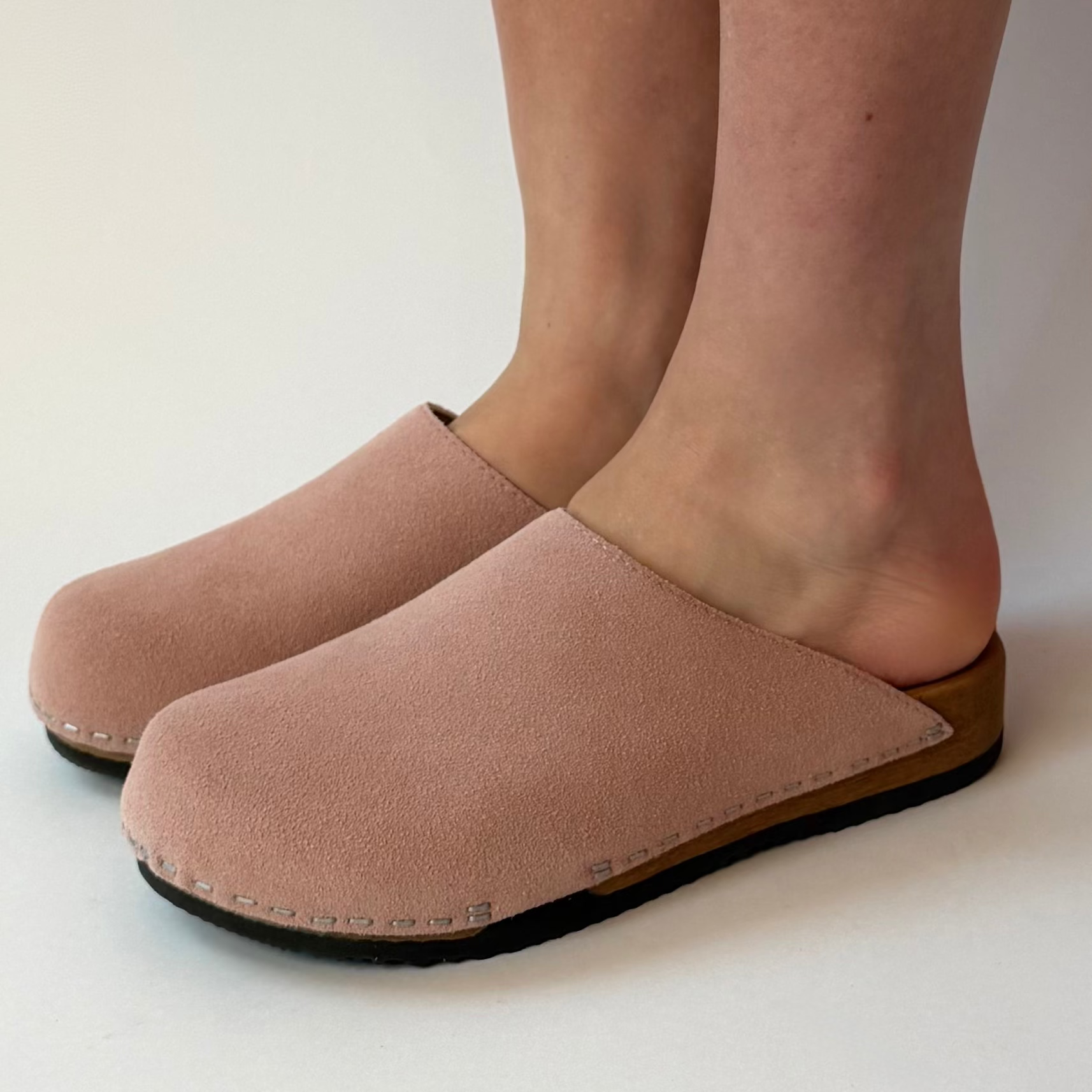 Beige clogs worn by a person on a white background
