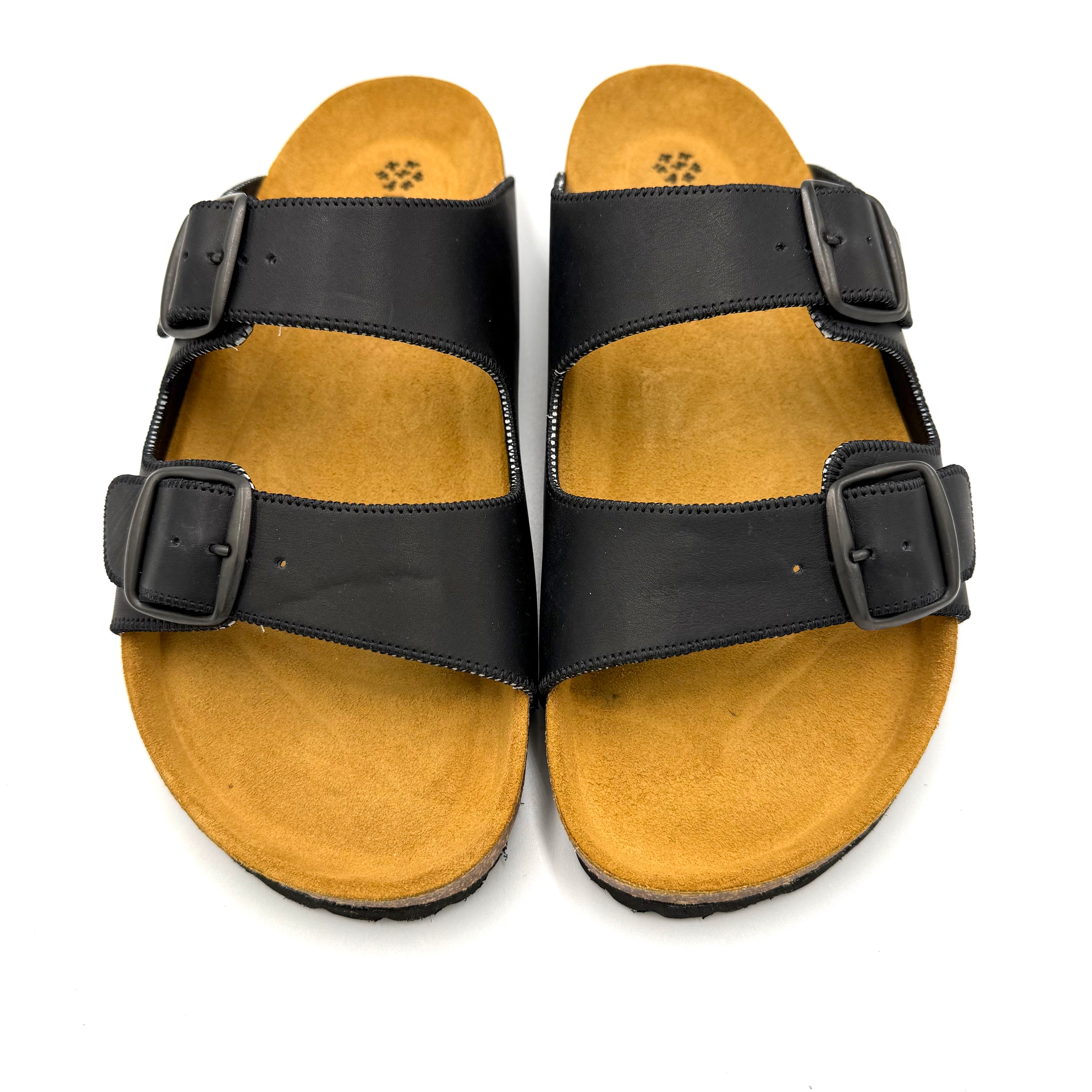 Pair of tan sandals with black straps on a white background