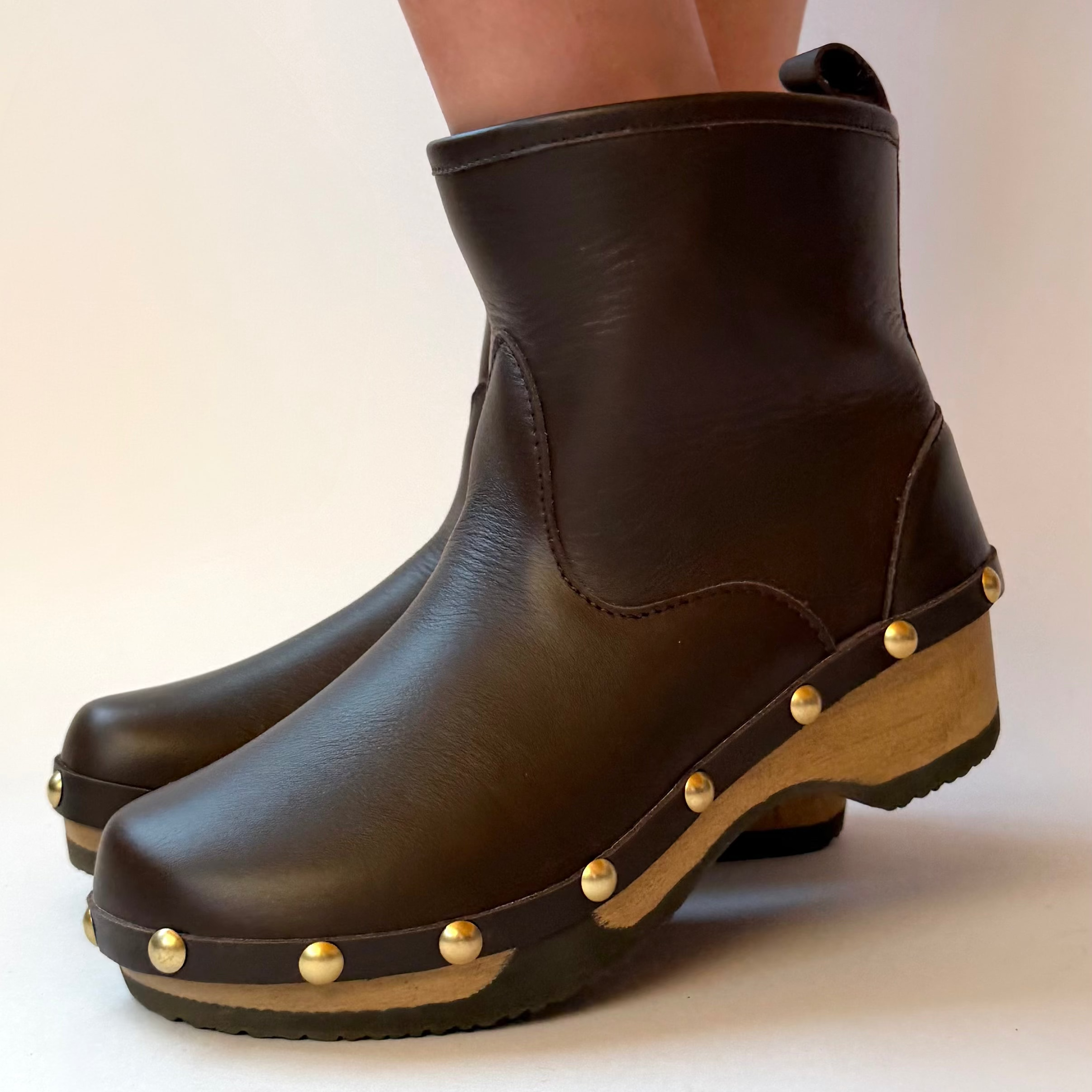 Pair of french rich brown leather studs boots on a white background