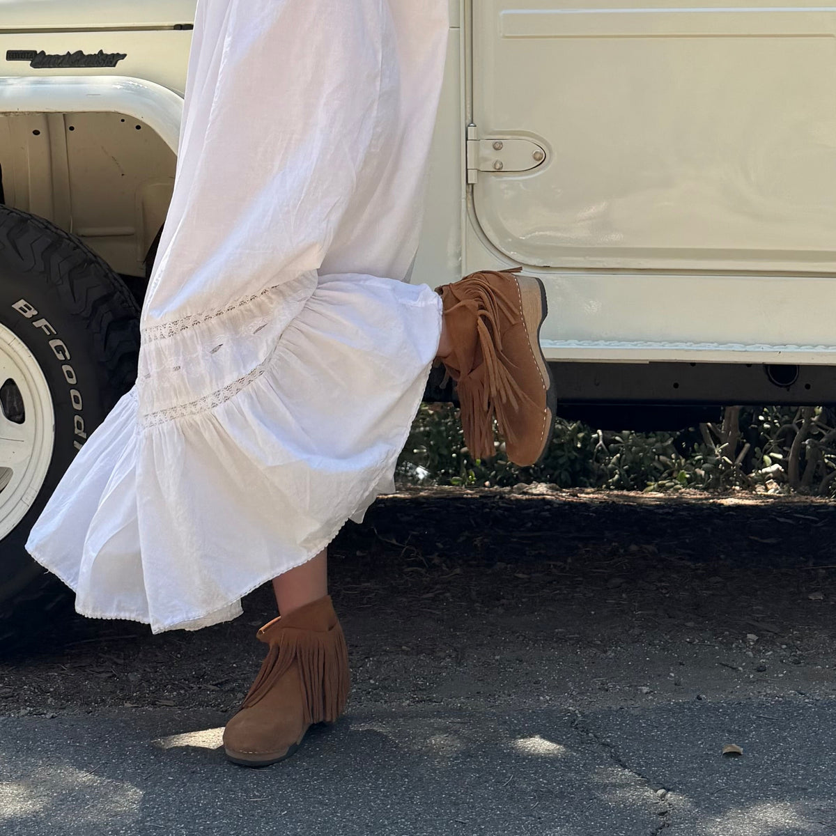 Pair of brown suede boots with fringes on a white background