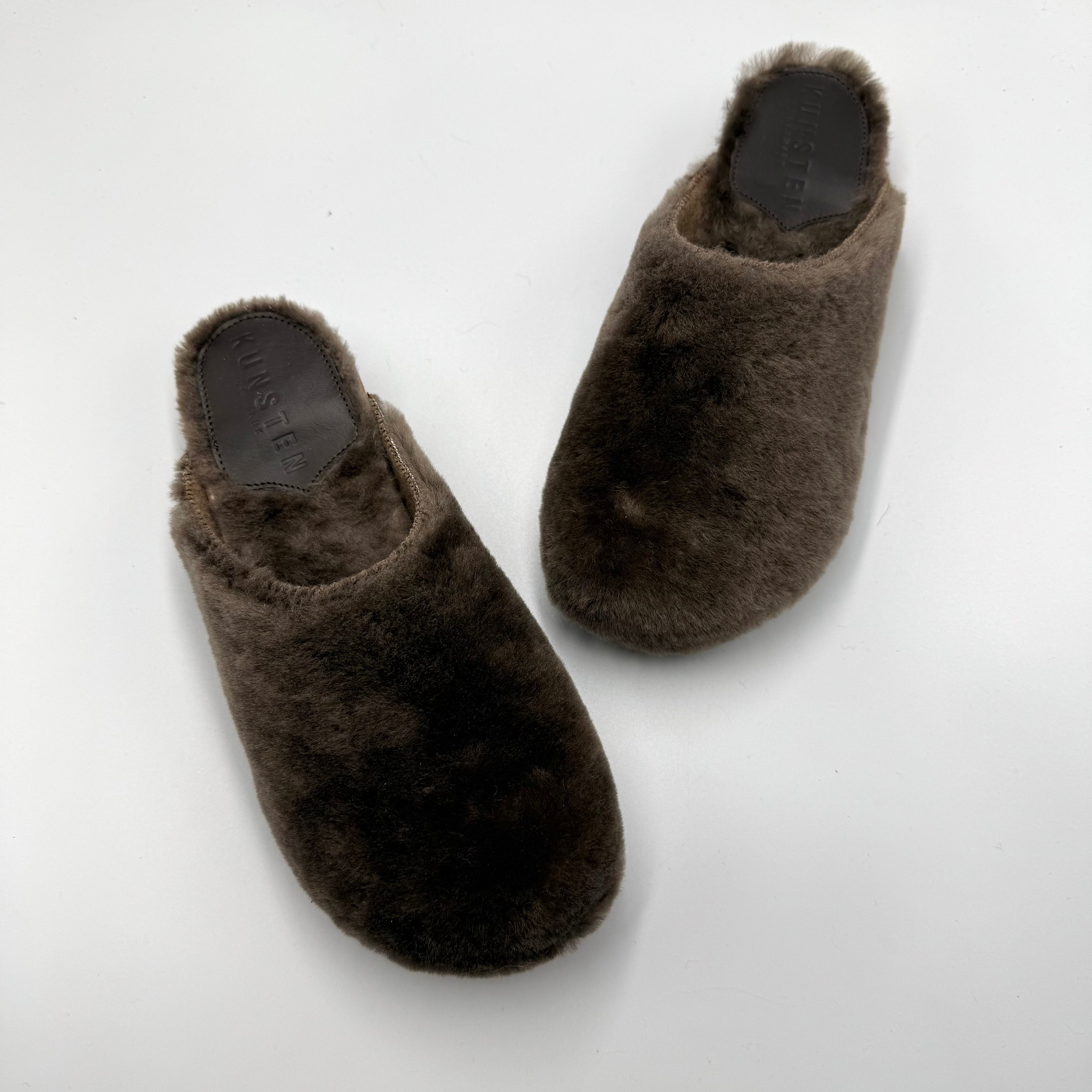 A pair of brown lambswoo cashmere slip-on slippers photographed from above on a plain white background.