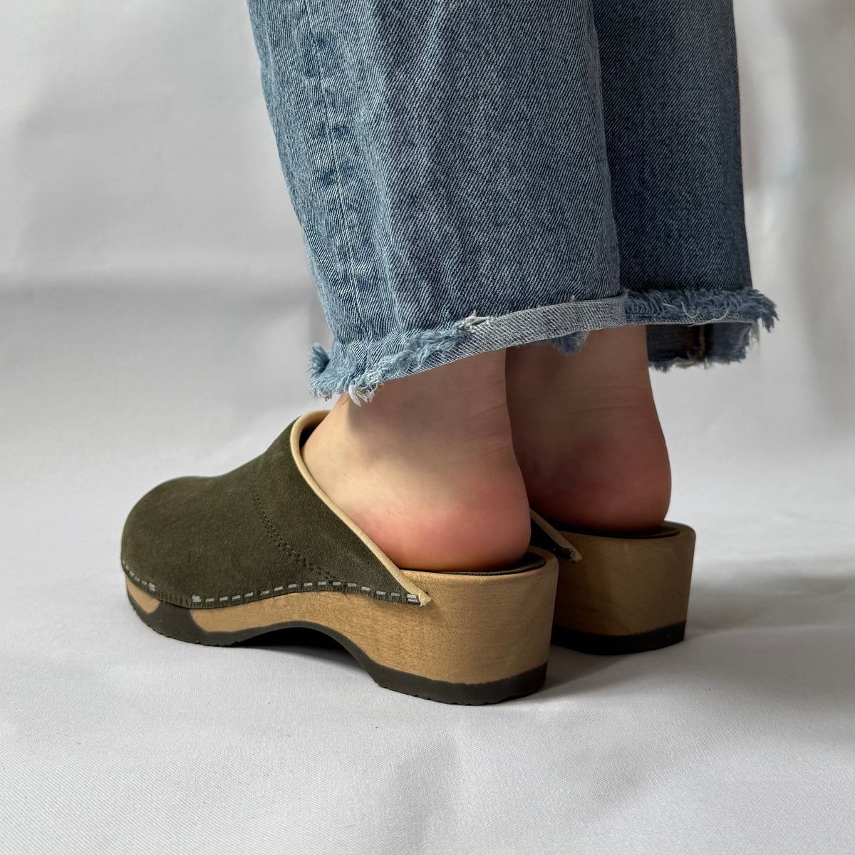 Person wearing green clogs on a white background