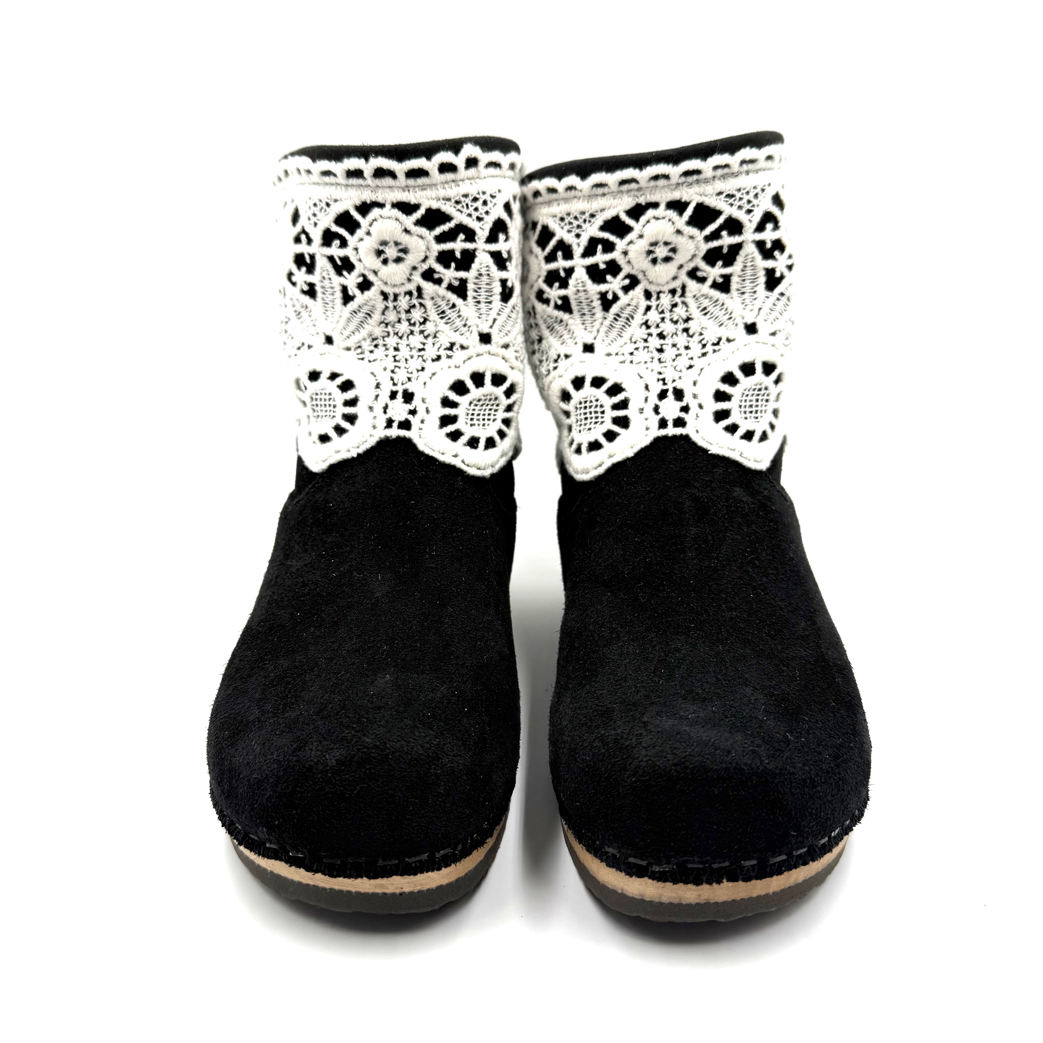 Black ankle boots with white lace detailing on a white background