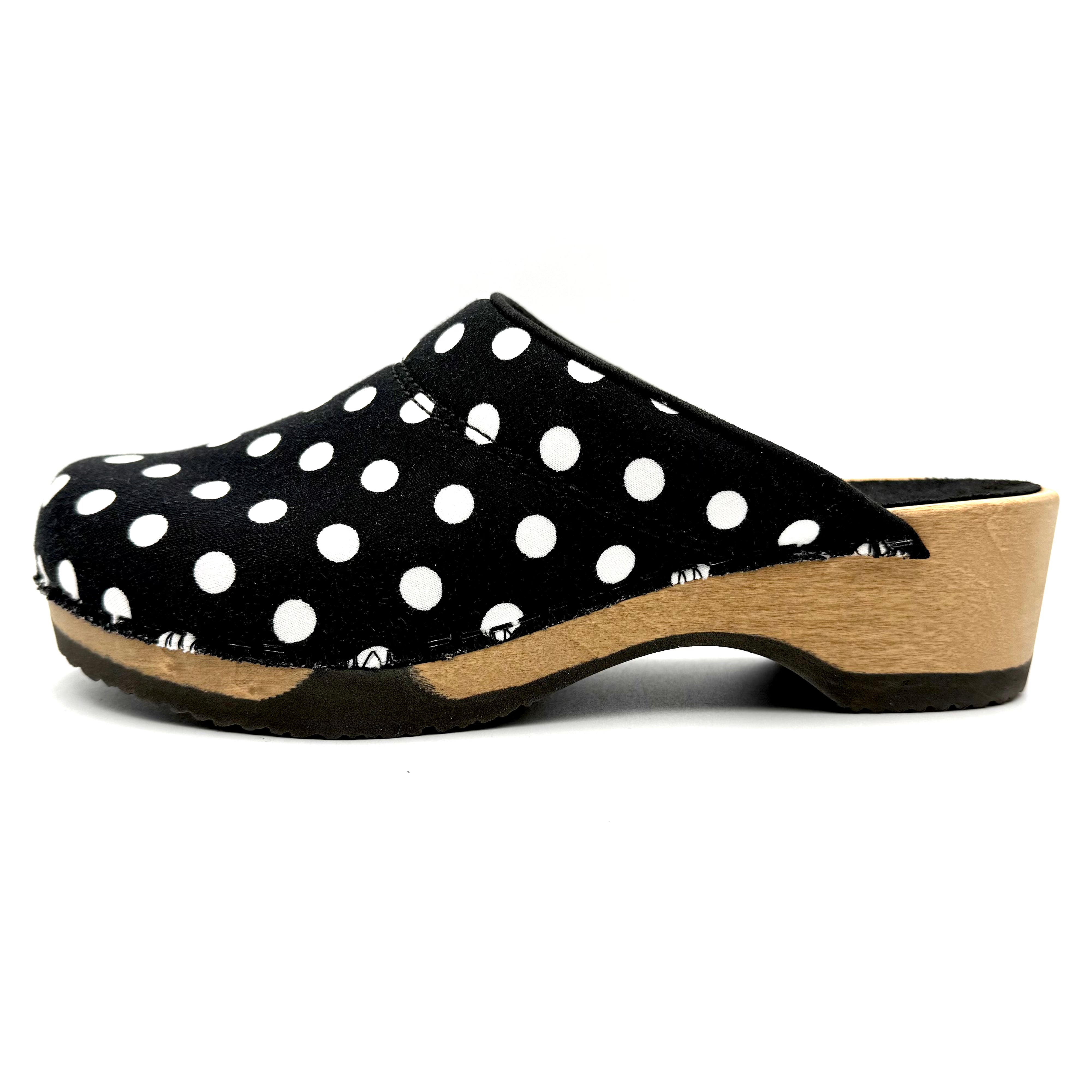 Black clog shoe with white polka dots on a white background
