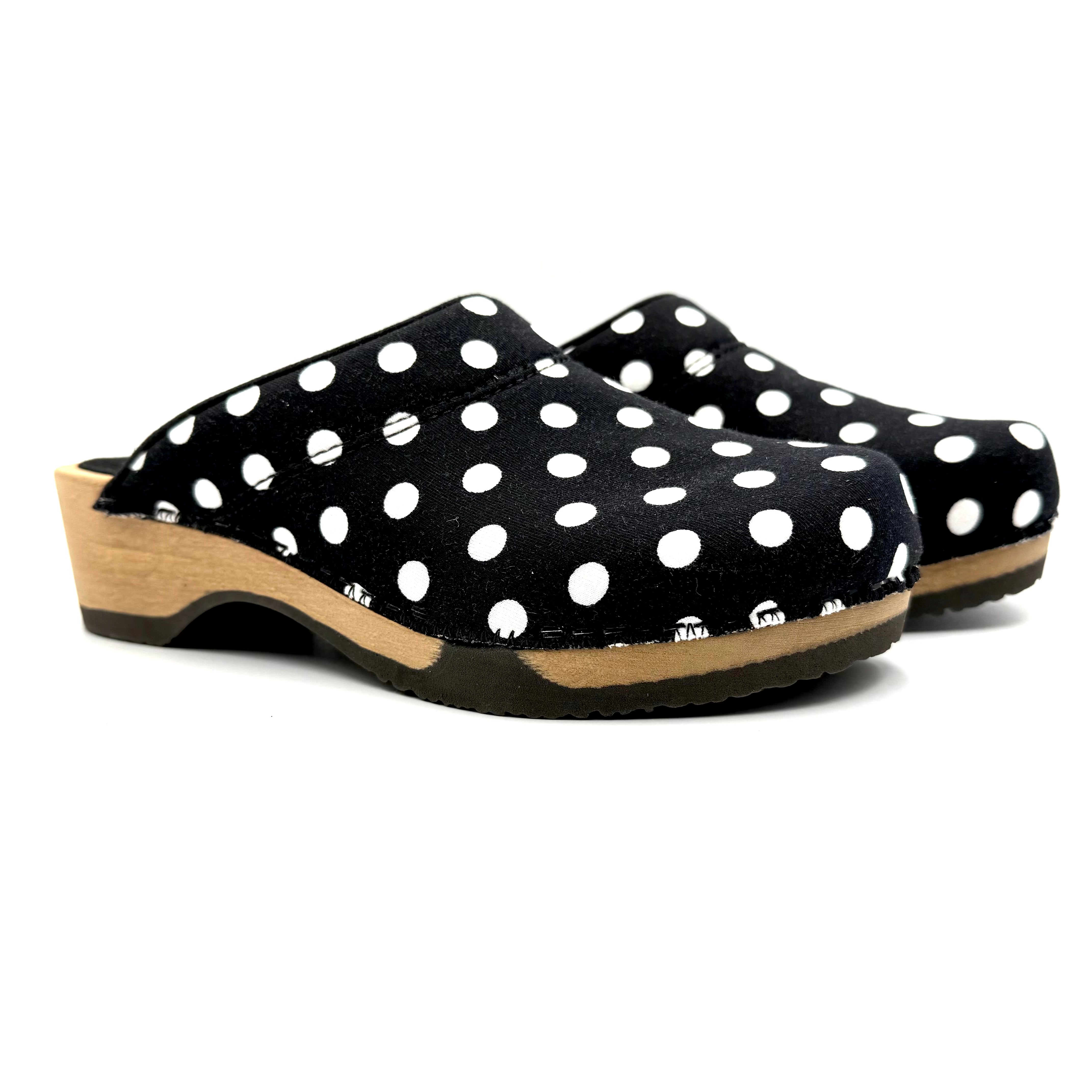 Black clogs with white polka dots on a white background