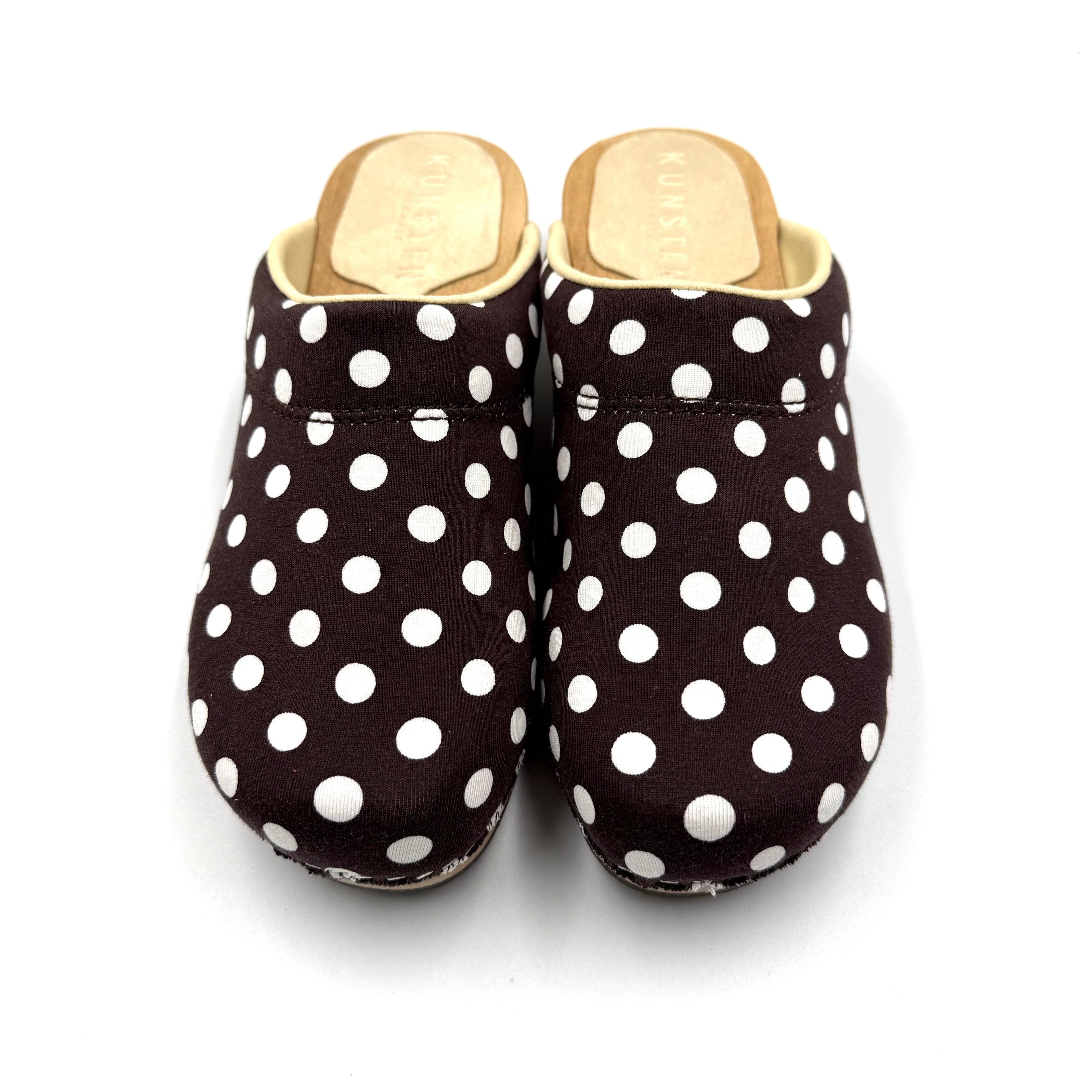 Pair of black slippers with white polka dots on a white background