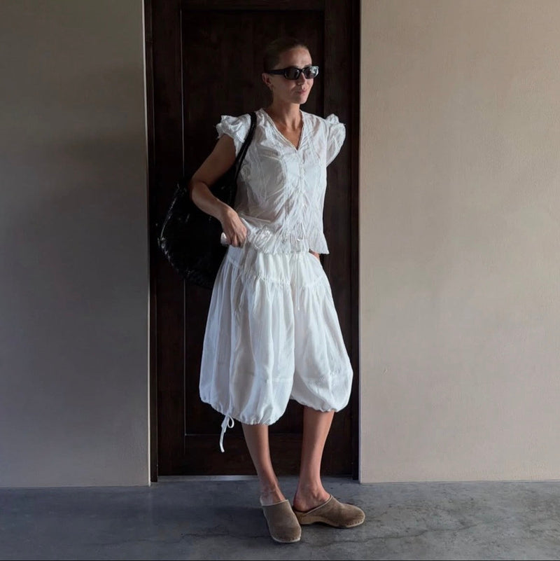Woman in a white dress wearing KUNSTEN clogs standing in a doorway