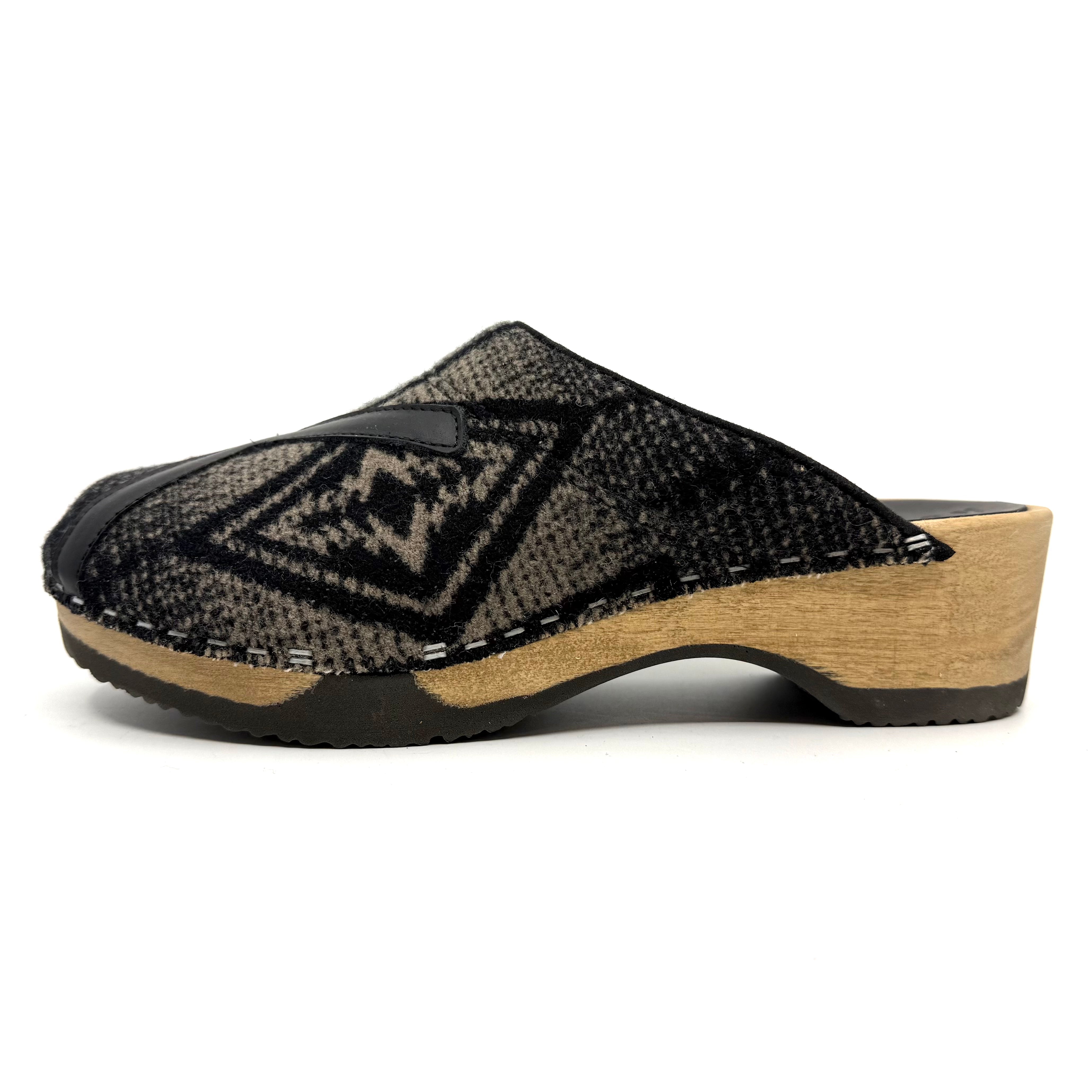 Black patterned clog shoe with wooden sole on a white background
