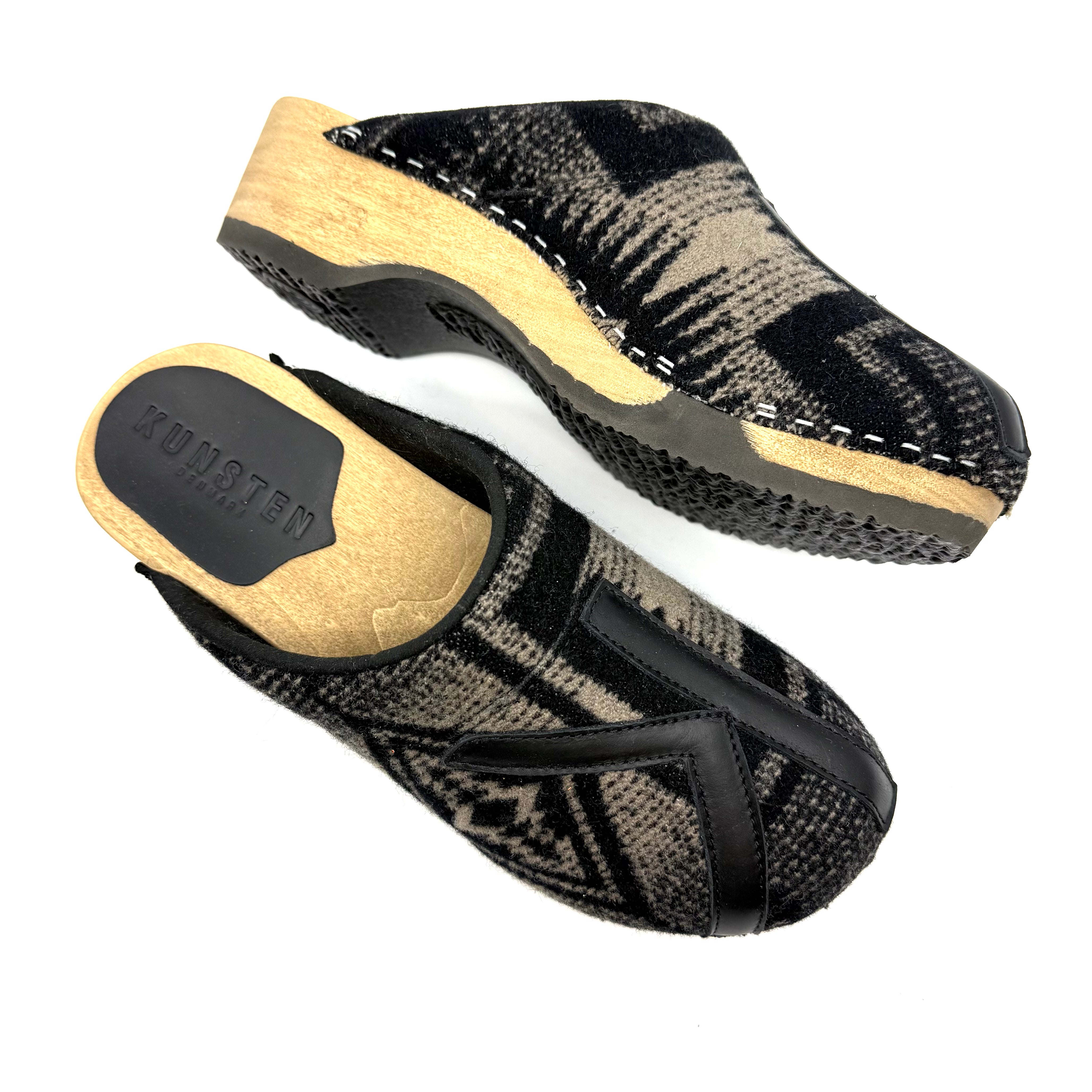 Pair of black and beige clogs on a white background