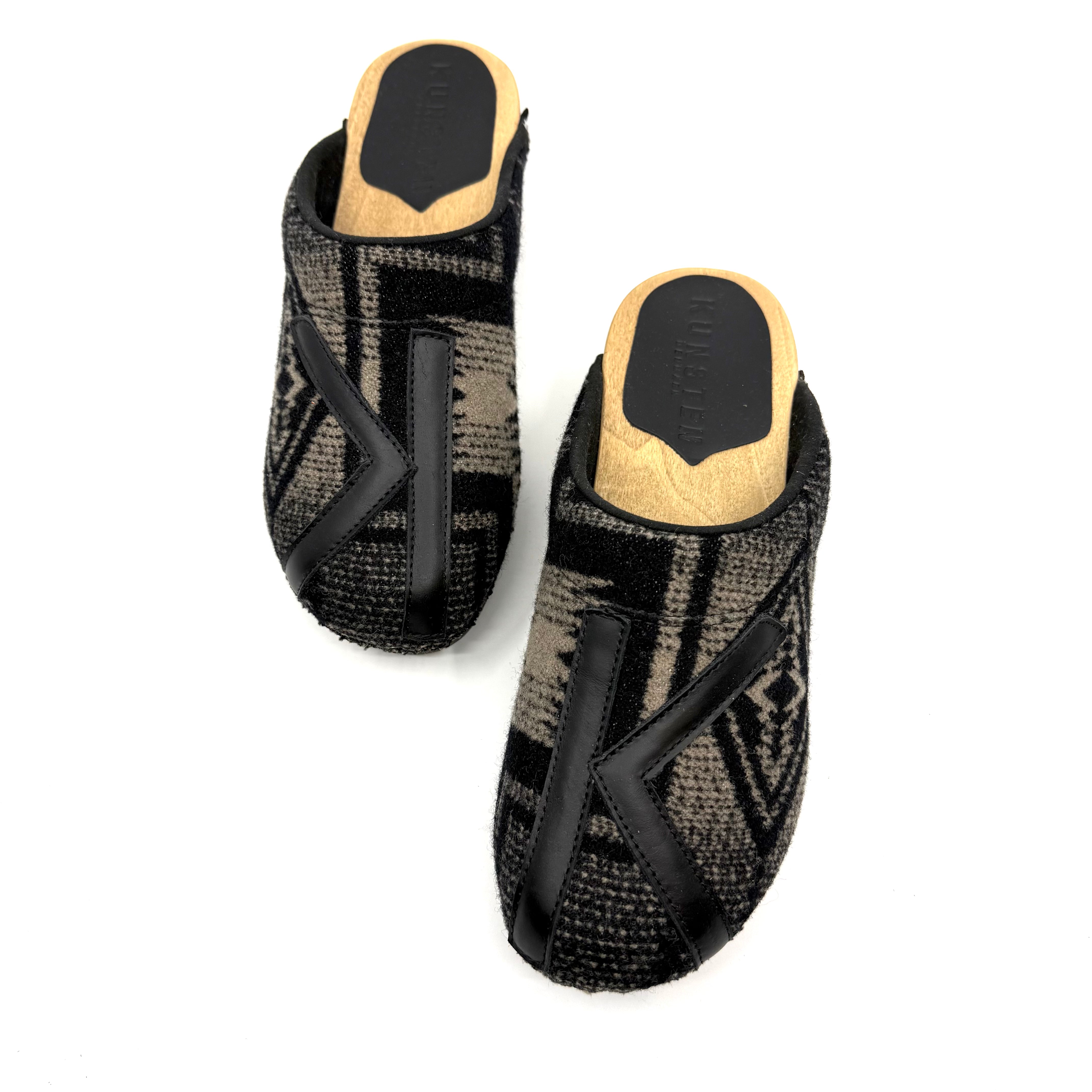 Pair of black and gray patterned slippers with wooden soles on a white background