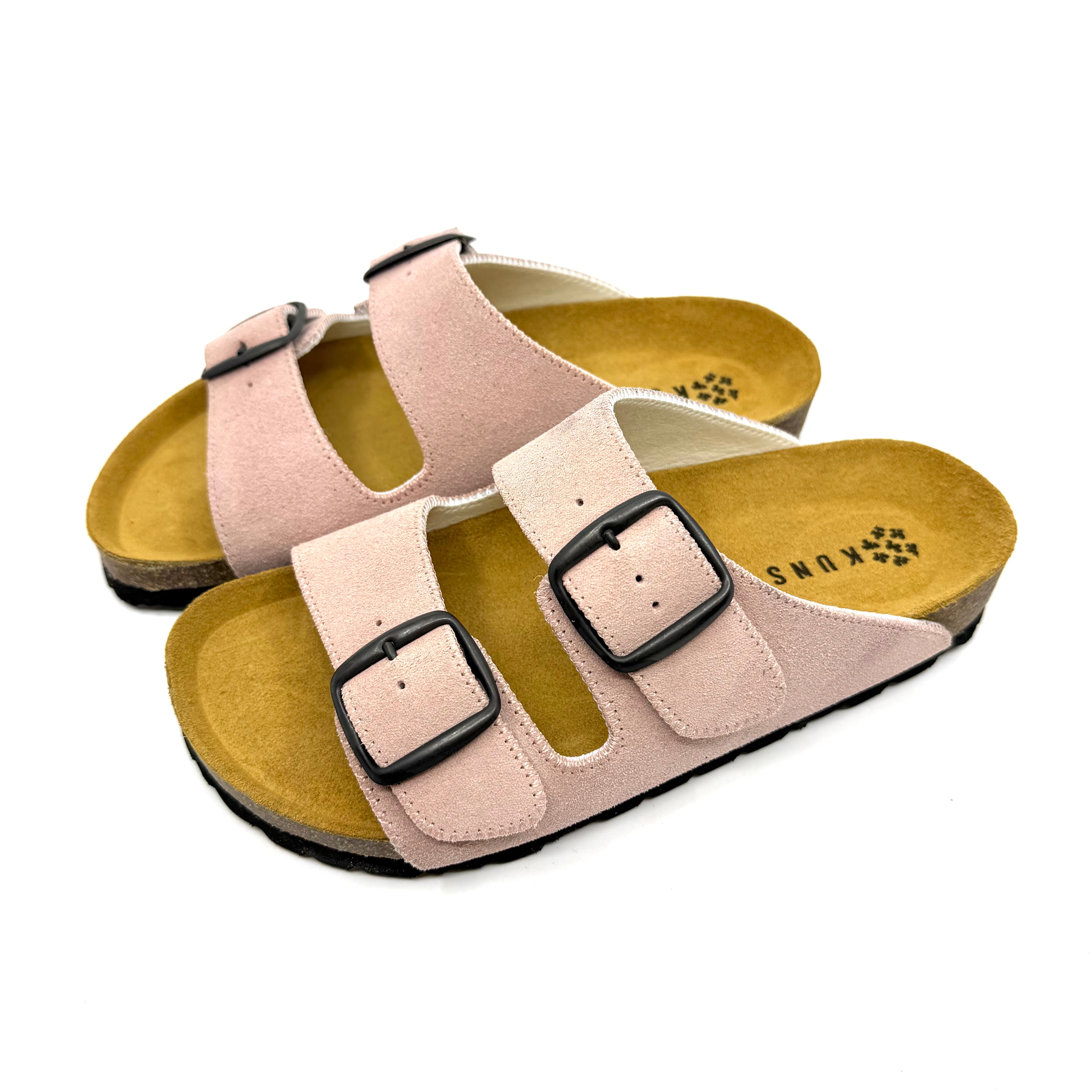 Pair of beige sandals with black buckles on a white background