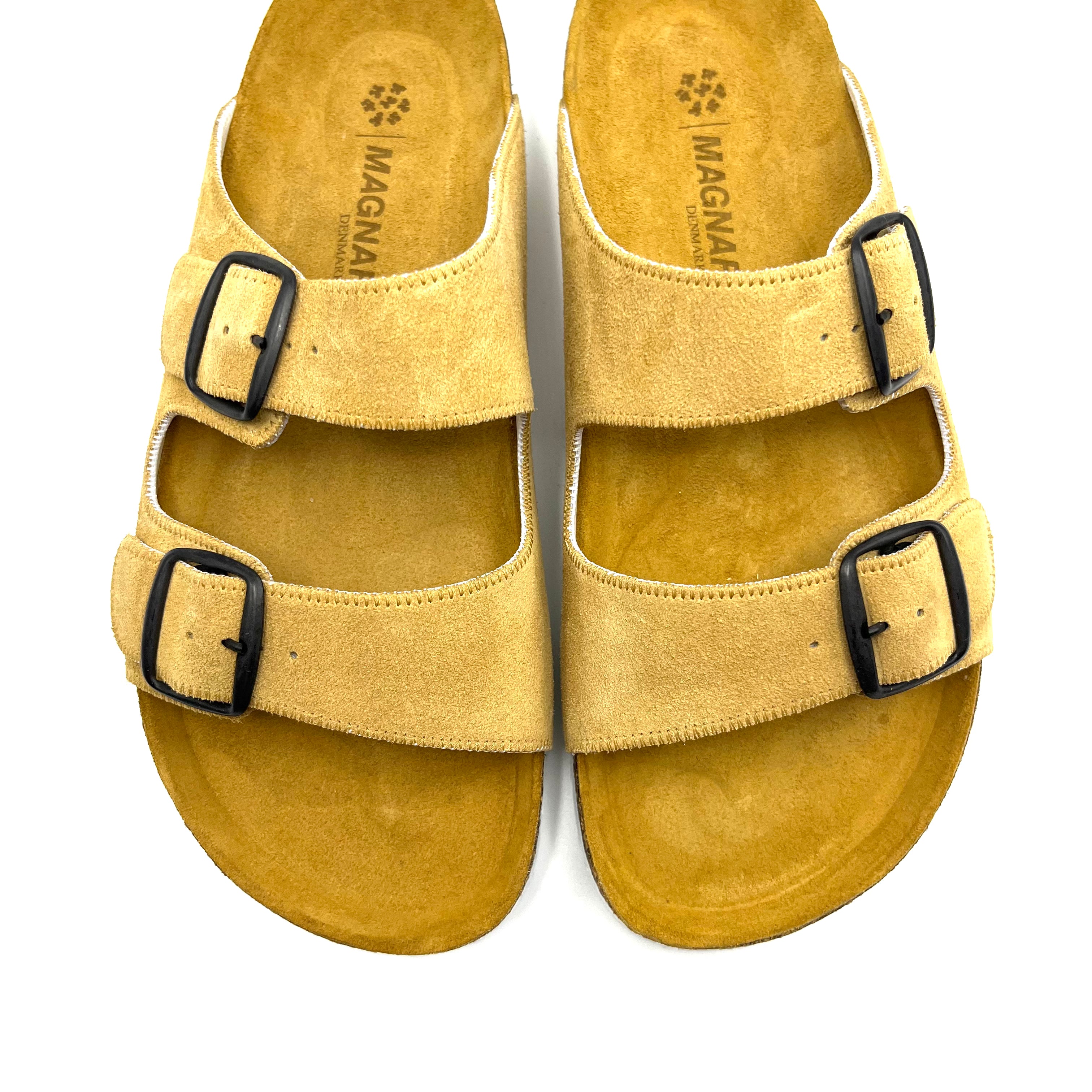 Yellow sandal with black buckles on a white background