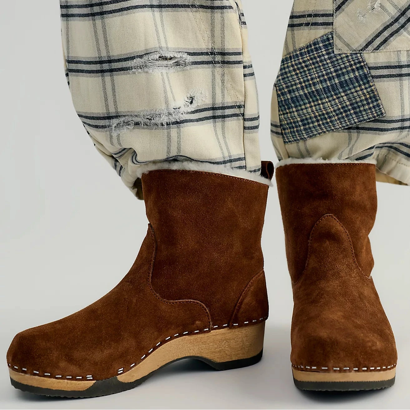 Pair of brown suede clog boots on a white background