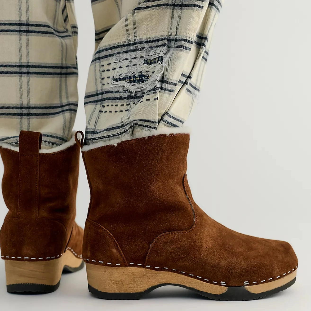 Brown suede slippers with white lining on a white background