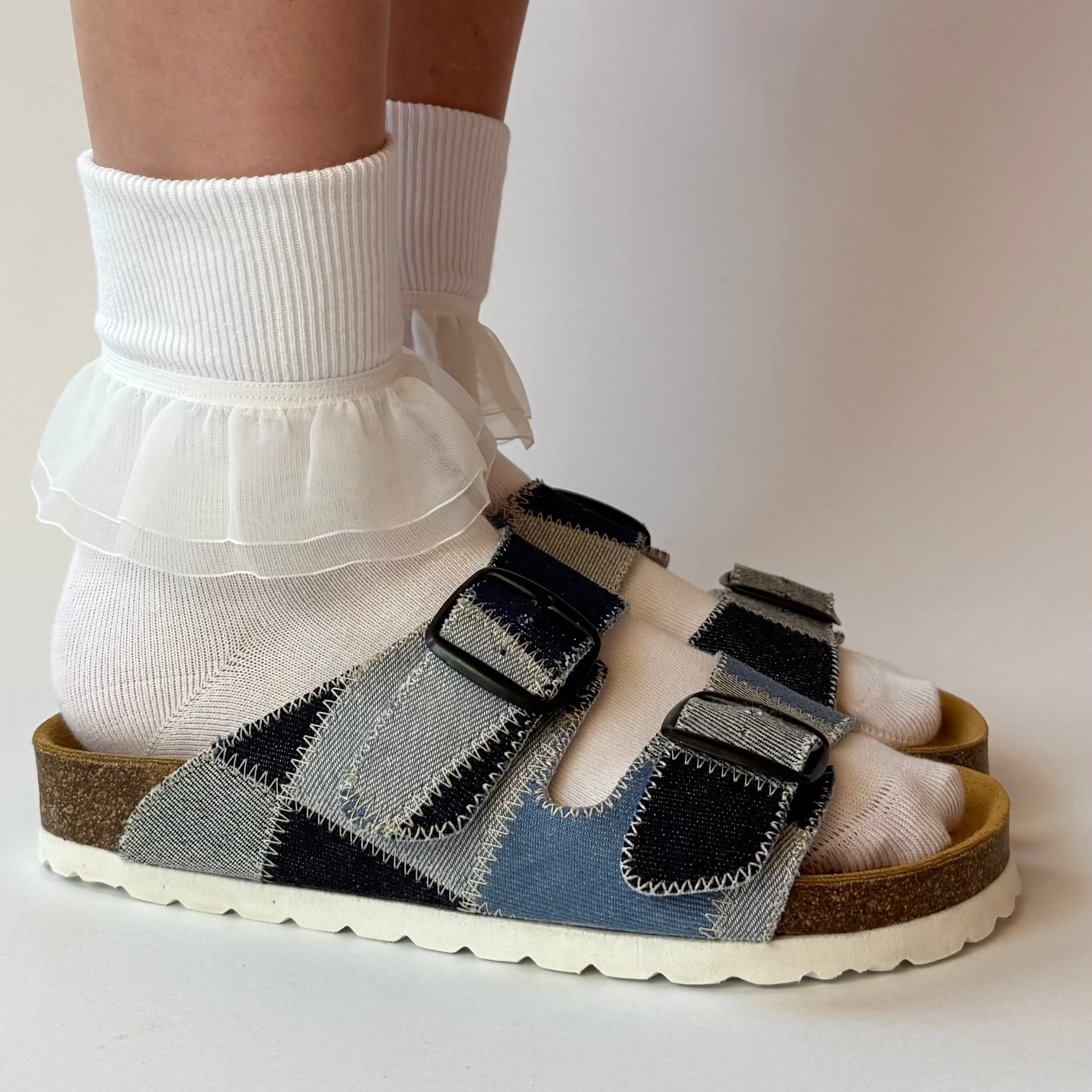Patchwork sandal worn with white socks on a plain background