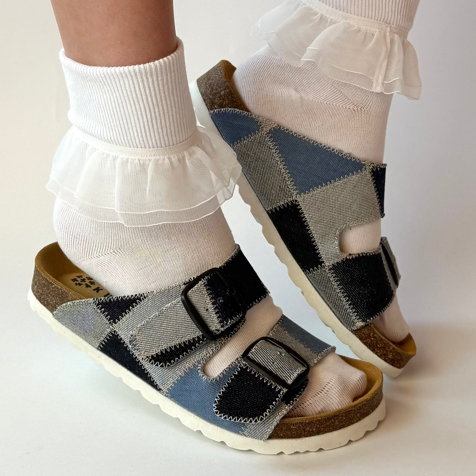 Person wearing checkered sandals with white socks on a plain background