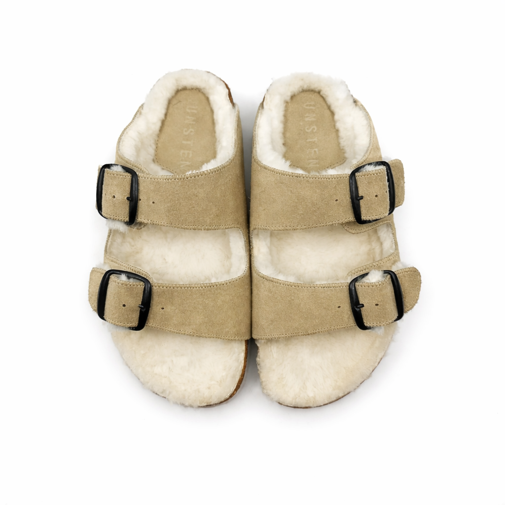 Pair of beige slippers with white fur lining on a white background