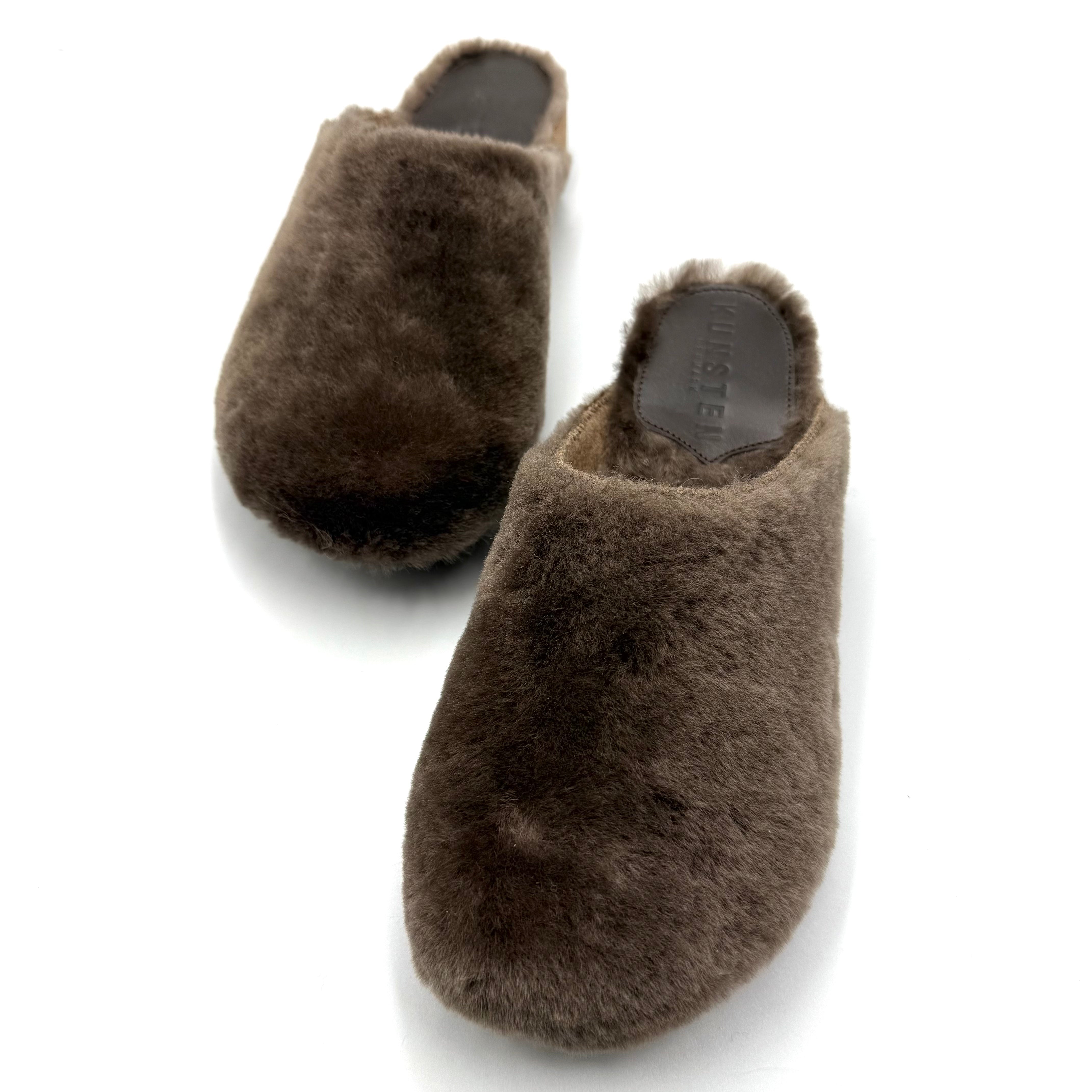 A pair of dark brown fuzzy slip-on slippers shown on a clean white background.