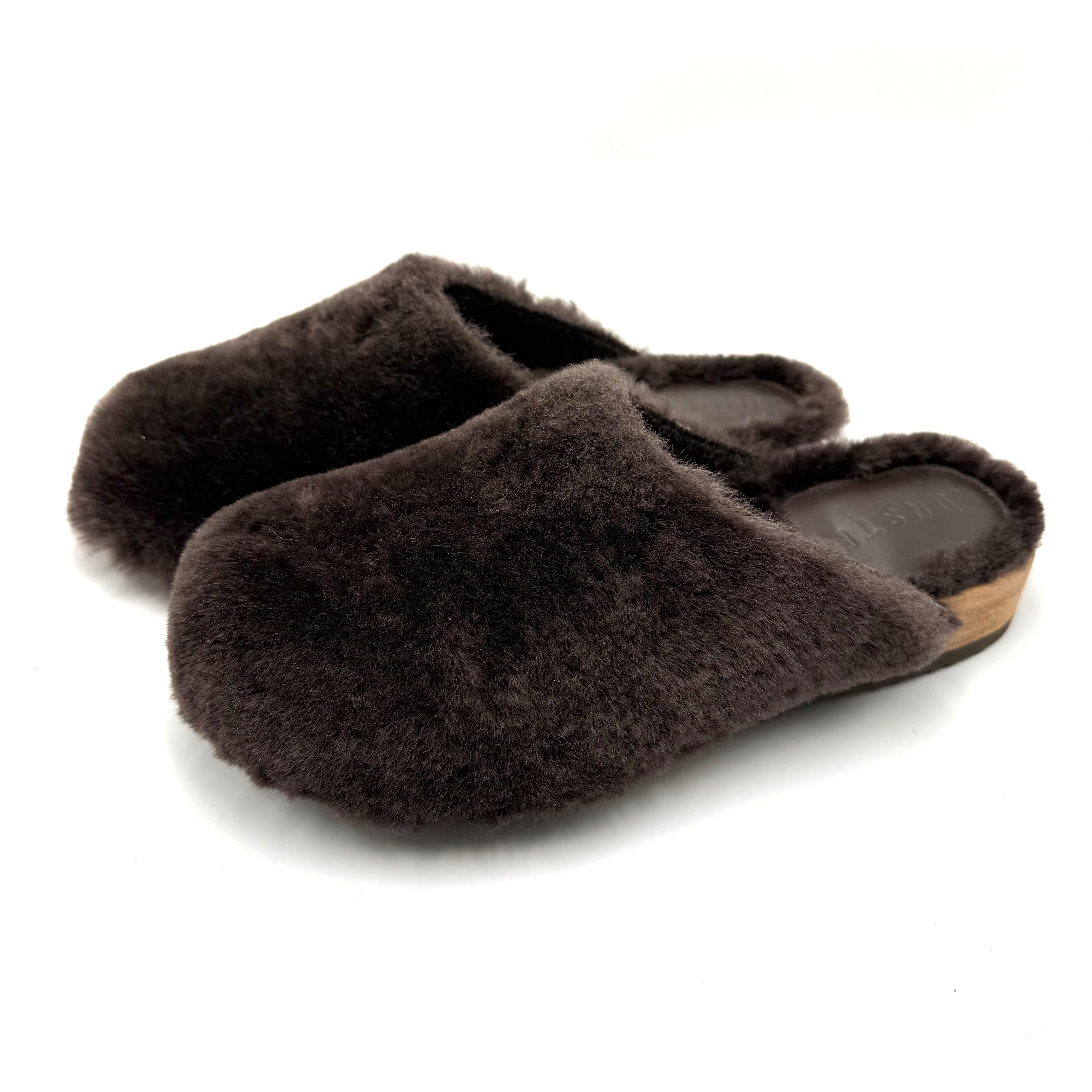 A pair of dark brown fluffy slip-on mule slippers with a light brown wood-look heel, shown on a white background.