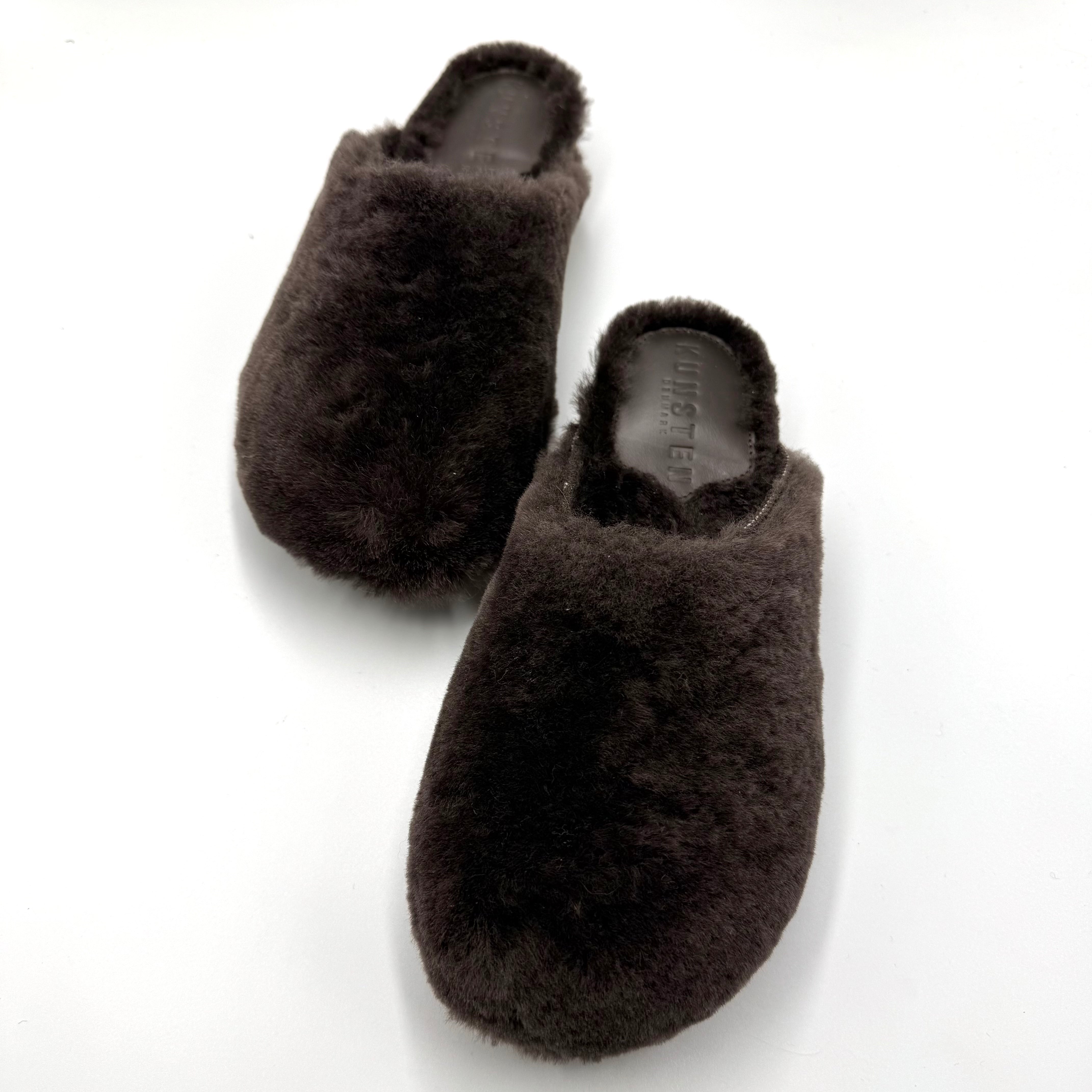 A pair of dark brown fluffy slip-on slippers photographed on a plain white background.