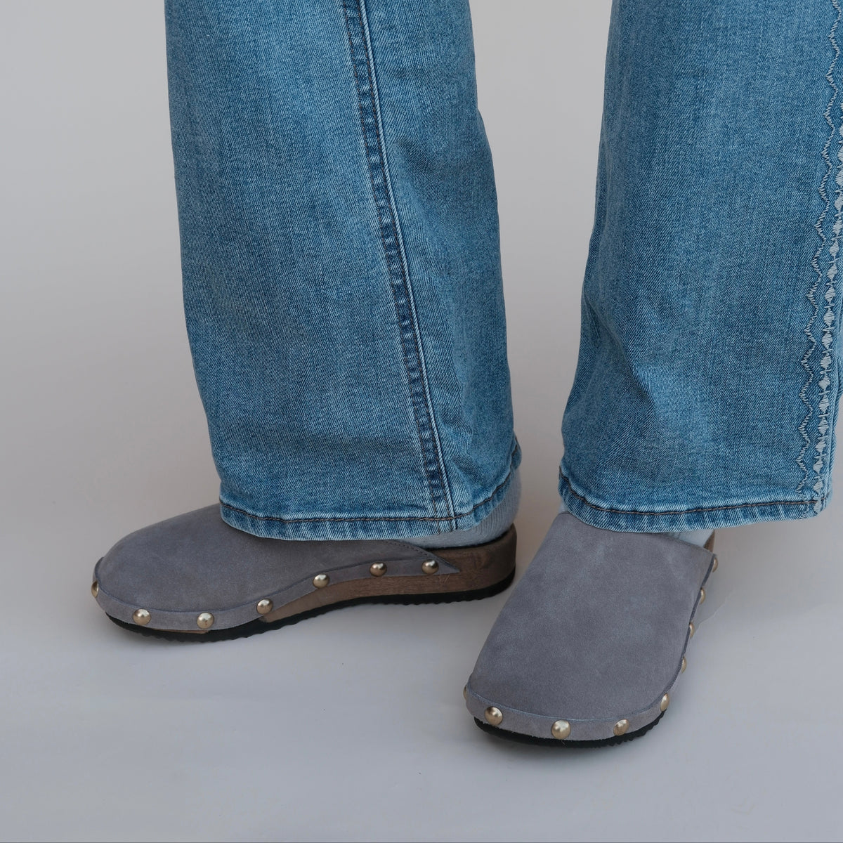 A model wearing KUNSTEN taupe suede clogs. 