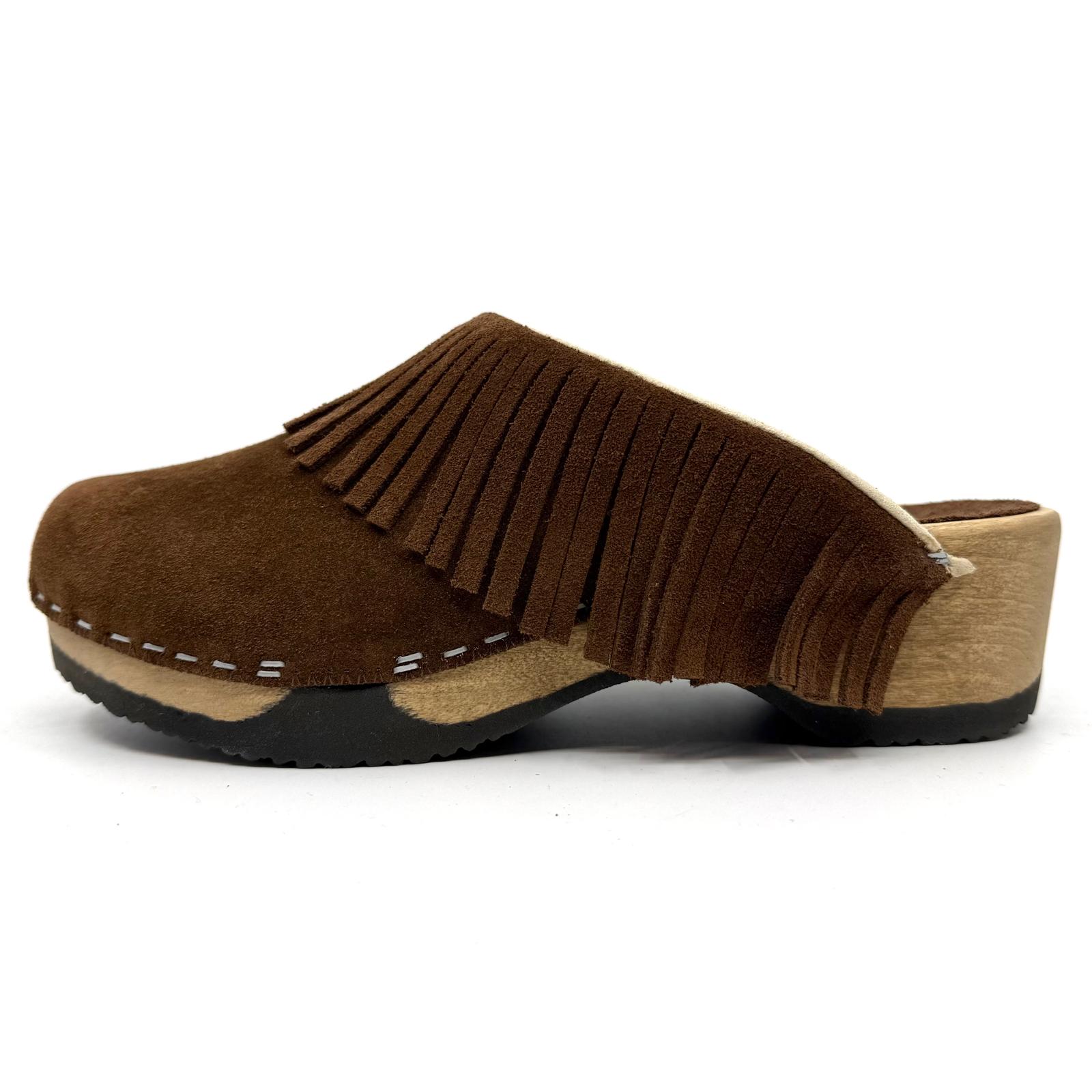 A single brown suede clog shoe with fringe detailing across the top, a light wood-look heel, and contrast stitching on a white background.