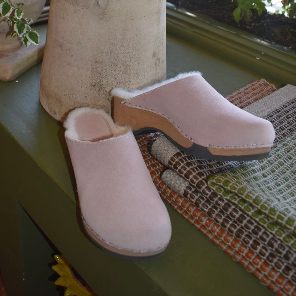 Embla clogs in Lily Rose suede with pure lambswool lining on a green bench