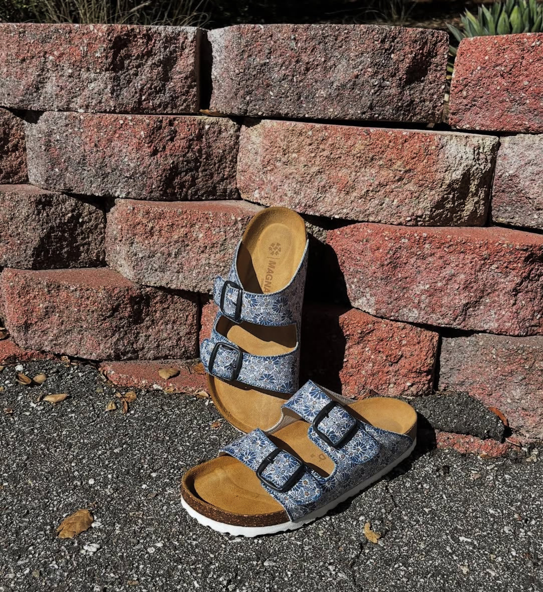 Pair of sandals with a stone wall and pavement background