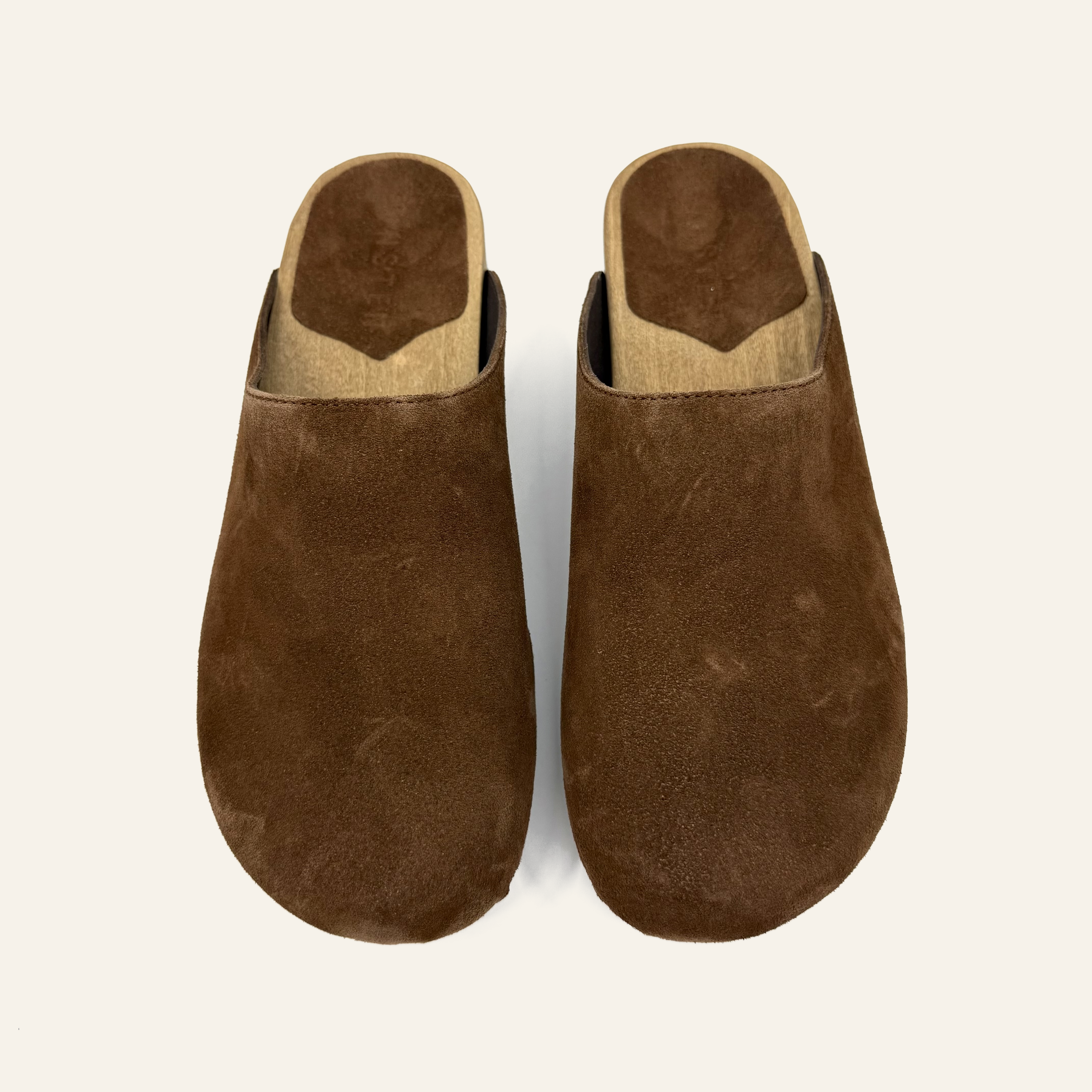 A pair of brown suede clogs with a light tan insole, shown from a top-down view on a light white background.