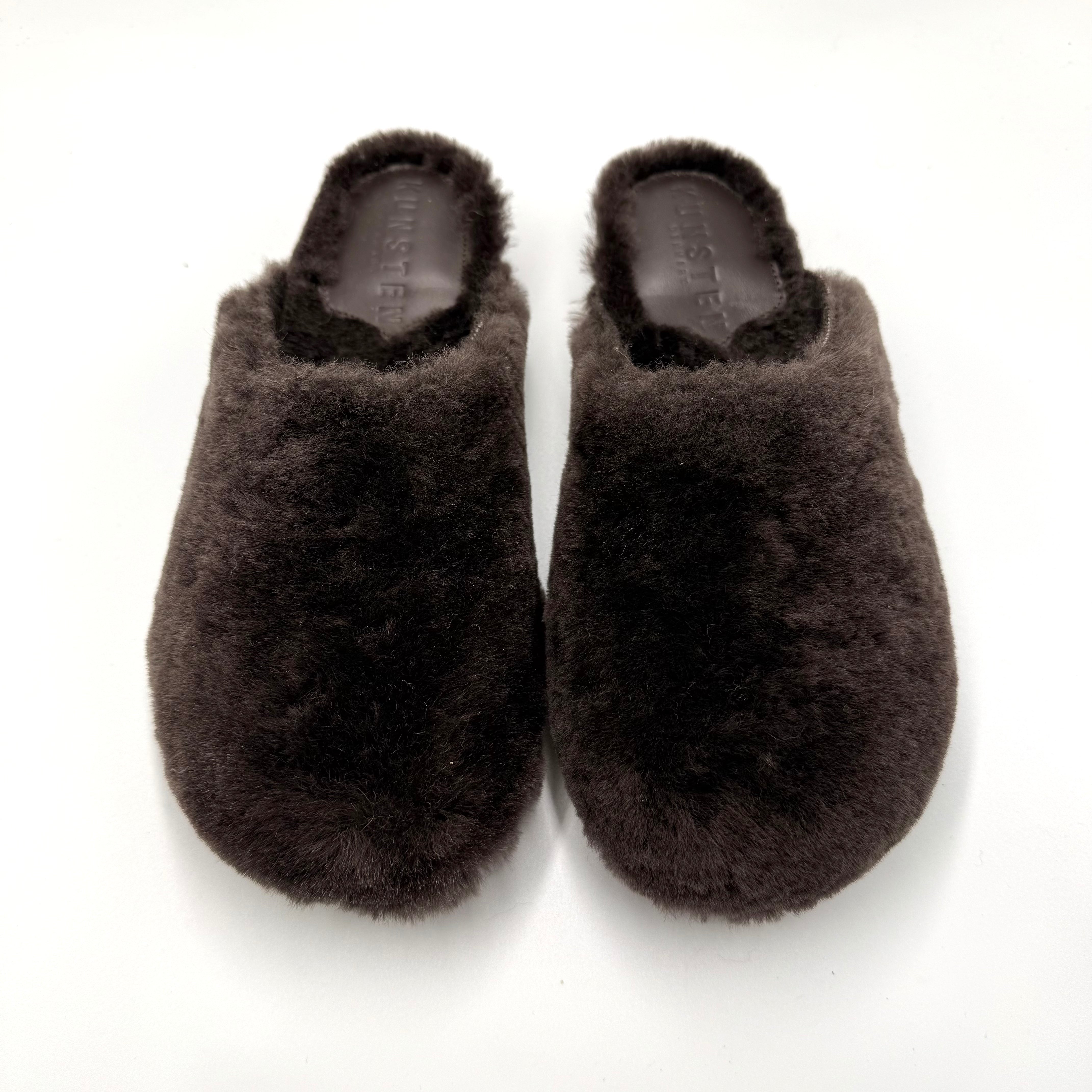 A pair of dark brown fluffy lambswool cashmere lip-on slippers shown from above on a plain white background.

