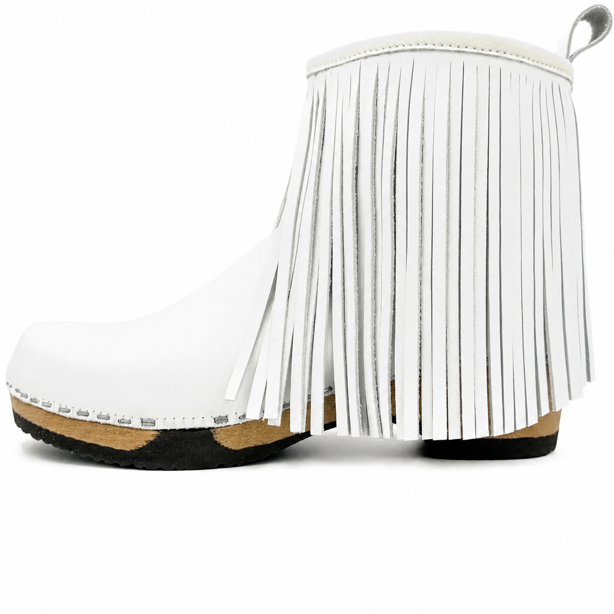 A white faux-leather ankle boot featuring a full fringe design on the side, a low black sole, a natural cork midsole, and a silver metal pull tab on the heel.